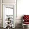 A dog is playfully peeking through a white mesh door curtain installed on a doorway. Produktbild-Vorschau