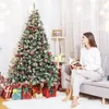 A woman is reading a book on a couch next to a decorated Christmas tree and presents. Produktbild-Vorschau
