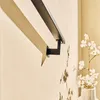 A black handrail bracket is mounted on a light-colored wall, with a shadow cast by the handrail. A vase with white flowers is visible on the right side. Anteprima dell’immagine prodotto
