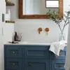 A modern bathroom vanity with blue cabinets, a white countertop and sink, and copper fixtures. Anteprima dell’immagine prodotto