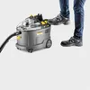 A person's feet are stepping on a Kärcher Puzzi 9/1 BP Waschsauger. Produktbild-Vorschau
