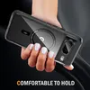 A hand holding a clear phone case with a magnetic ring inside, against a dark background. Náhled obrázku produktu