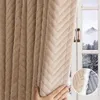 A hand is shown adjusting a thick, plush, beige curtain with a chevron pattern, which is hanging in front of a window showing a snowy mountain landscape. A close-up inset shows the texture and lining of the curtain. Náhled obrázku produktu