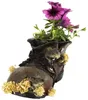 A decorative planter shaped like a boot, with mice figures and flowers. Produktbild-Vorschau