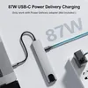 A USB-C hub is shown connected to a laptop and plugged into a wall adapter, illustrating its charging capabilities. Produktbild-Vorschau