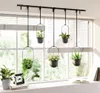Hanging planters with plants on a windowsill in front of a window with blinds. Produktbild-Vorschau