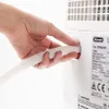 A hand is shown connecting a white corrugated hose to a white appliance. Voir les images du produit