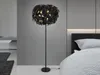 A bedroom scene with a floor lamp next to a bed. Voir les images du produit