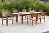 A wooden dining set with six chairs and a table is placed on a patio surrounded by greenery and flowers. Produktbild-Vorschau
