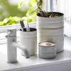 A bathroom counter with a faucet and storage containers. Anteprima dell’immagine prodotto