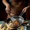 A person wearing a leather apron is cooking a steak in a pan with butter, garlic, and rosemary. Náhľad obrázku produktu