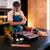 A man is grilling food on an electric grill in a kitchen. Voir les images du produit