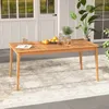An outdoor dining table set on a rug with a plant and fruit on it, in front of a white building with windows. Náhled obrázku produktu