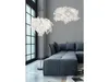 A modern living room with a sectional sofa, a floor lamp, and a pendant light, all featuring a white, leafy design. Produktbild-Vorschau