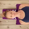A woman is lying on her back on an acupressure mat and pillow set, which is placed on a wooden deck. Produktbild-Vorschau