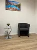 A waiting area with a chair, side table, and artwork. Produktbild-Vorschau
