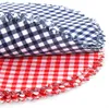 Two stacks of round fabric coasters with a gingham pattern, one red and white, the other blue and white. Produktbild-Vorschau