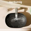 A black oval washbasin with water flowing from a gray faucet. Anteprima dell’immagine prodotto