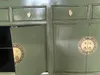 A close-up view of a green wooden sideboard with brass hardware. Voir les images du produit