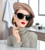 A decorative bust of a woman wearing a beret, sunglasses, and a turtleneck sweater, placed on a table with a blurred background of a kitchen or bathroom. Produktbild-Vorschau