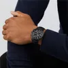 A close-up shot of a person's arm wearing a black watch. Voir les images du produit