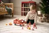 A young boy plays with a wooden fire truck and accessories on a rug in a room with a Christmas tree and gifts. Produktbild-Vorschau