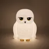 A white owl lamp with yellow eyes and black accents, lit from within, sits on a neutral background. Anteprima dell’immagine prodotto