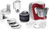 A collection of kitchen appliance parts and accessories, including a stand mixer, blender, food processor attachment, and various mixing attachments, arranged on a white background. Produktbild-Vorschau