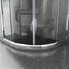 A close-up view of the bottom section of a curved shower enclosure, showing the metallic frame and the black shower base. Voir les images du produit