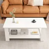 A white coffee table with items on it, placed in front of a brown leather couch. Náhled obrázku produktu