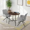 A small dining set with two chairs and a round table in a room with a plant and artwork on the wall. Produktbild-Vorschau