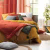A bedroom scene with a bed dressed in colorful bedding, pillows, and curtains. Náhľad obrázku produktu