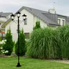 A garden scene with a lamppost in the foreground and a house in the background. Produktbild-Vorschau