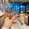 A hand holding a clear phone case with silver accents, with a blurred background of a cafe or store. Produktbild-Vorschau