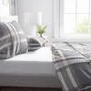 A close-up view of a bed with plaid bedding. Produktbild-Vorschau