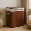 A bamboo laundry basket with two compartments is shown in a room setting. Produktbild-Vorschau