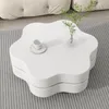 A white, flower-shaped coffee table with a cup and saucer and a small vase with greenery on it. Voir les images du produit