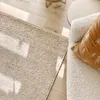 A close-up view of a rug and a sofa with a pillow in a room with natural light. Voir les images du produit