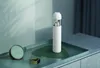 A white Xiaomi vacuum cleaner is placed on a tray with a clock and a watch. Produktbild-Vorschau