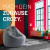 A modern living room scene with a gray beanbag chair in the foreground and colorful walls and furniture in the background. Podgląd zdjęcia produktu