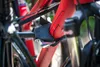 A close-up view of a bicycle rack attachment, showing straps and a metal buckle securing a red bicycle frame. Produktbild-Vorschau