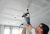A man is using a Bosch drill to make a hole in a ceiling. Anteprima dell’immagine prodotto