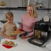 A woman and a child are in a kitchen, holding a tray of freshly baked cookies near an air fryer. Produktbild-Vorschau