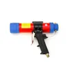 A pneumatic cartridge dispenser gun, also known as a silicone gun, is shown against a white background. It has a red barrel with a yellow label and blue end caps. The handle is black with a silver trigger and a metal connector at the bottom. Podgląd zdjęcia produktu