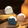 Three cloud-shaped LED night lights are displayed on a surface next to books and a vase. Produktbild-Vorschau