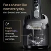 A Braun electric shaver is shown in its SmartCare Center, with water flowing to clean the shaver head. Náhľad obrázku produktu