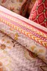 A close-up view of folded bedding with a floral pattern and decorative borders. Produktbild-Vorschau
