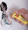 A hand is using a yellow wire stripper tool to strip a white wire from a bundle of colorful wires connected to a white junction box mounted on a white wall. Produktbild-Vorschau
