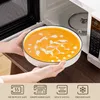 A person is holding a bowl of soup in front of an open microwave. Náhled obrázku produktu