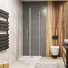 A modern bathroom with a glass shower enclosure, toilet, and wooden accents. Produktbild-Vorschau
